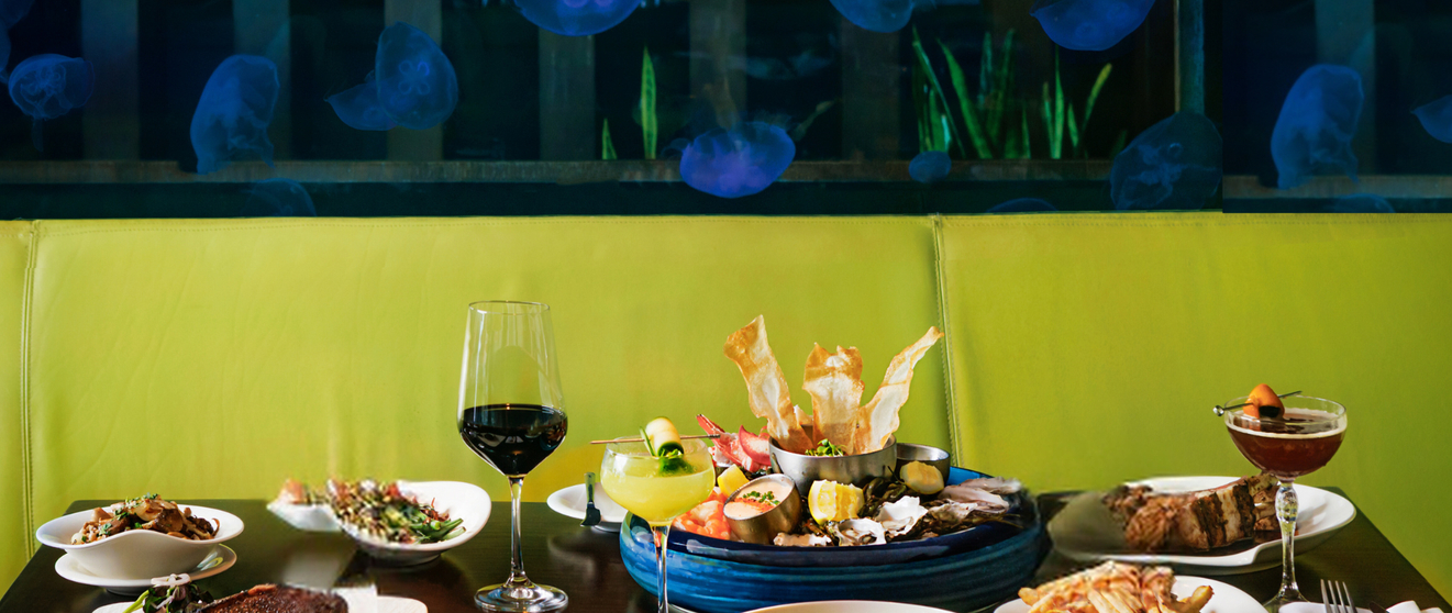 Dining table set with plates of food, wine glasses, and a jellyfish-themed background.
